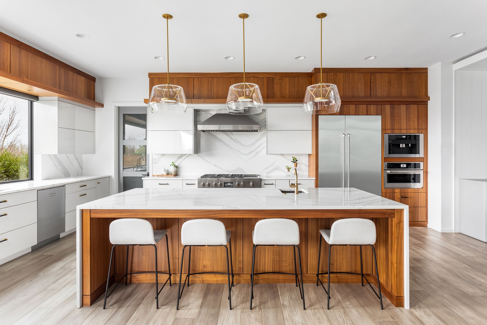 Beautiful kitchen in new luxury home with waterfall quartz island, pendant lights and hardwood floors.
