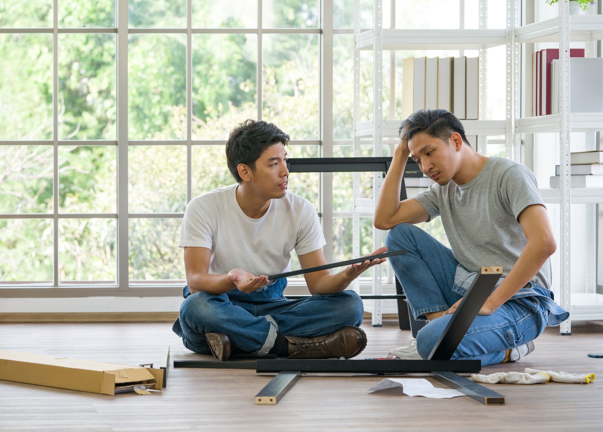 House renovation service. Two carpenters discussed the type of bench being assembled. Morning work atmosphere in the living room. Handyman installing wooden bench in new house.